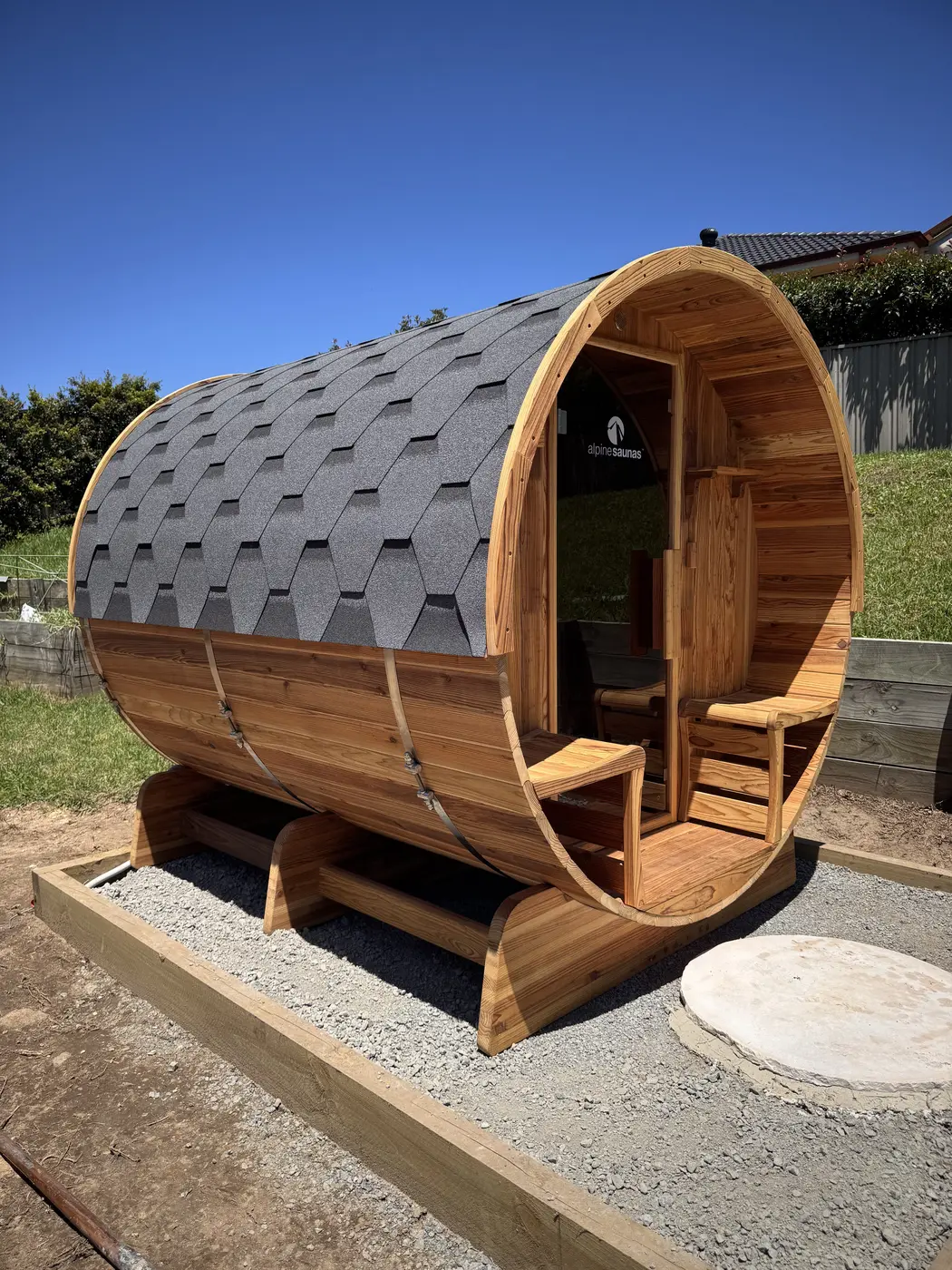 Barrel sauna on a gravel pad with its electrical connection