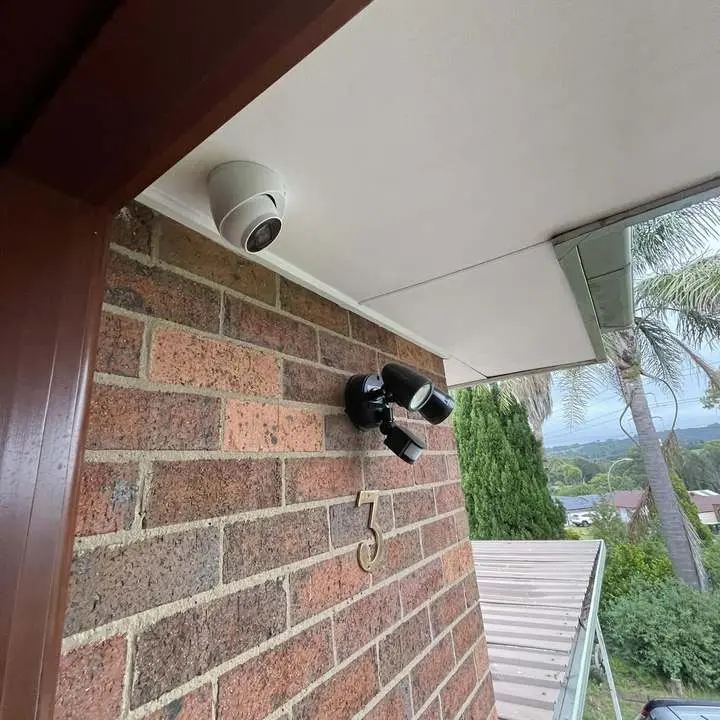 CCTV camera with sensor light on a brick home