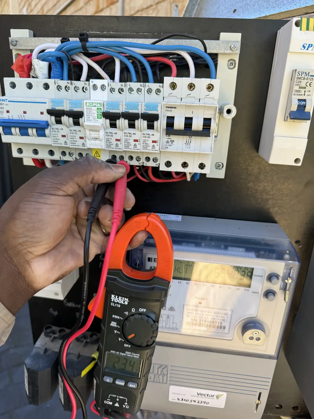 Mutsa testing a switchboard with a clamp meter during fault finding